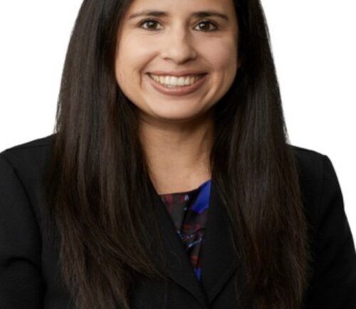 Professional headshot of Linda Gutierrez in dark business suit smiling at camera