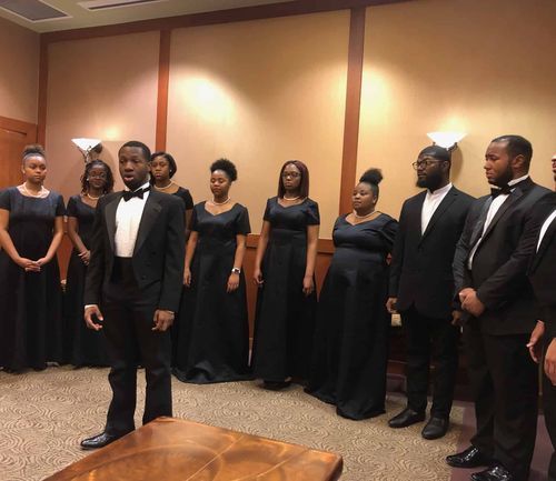 Choir members in formal black attire performing at MLK Day celebration event