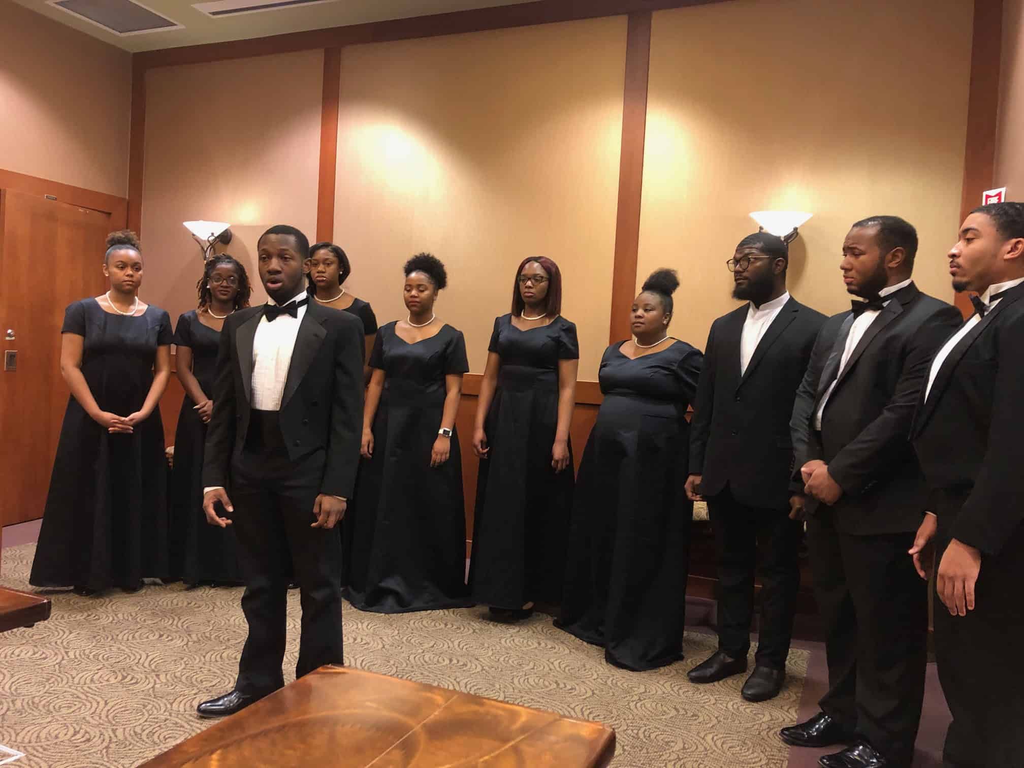 Choir members in formal black attire performing at MLK Day celebration event