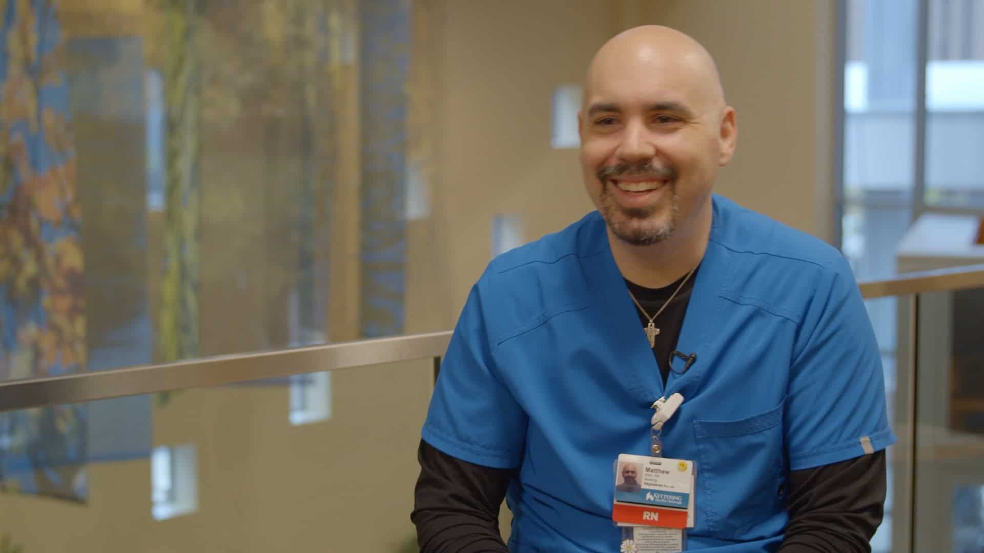 Healthcare professional in blue scrubs smiling while sitting in modern hospital lobby