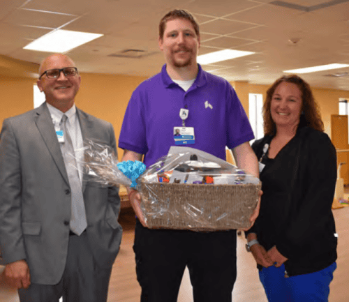 Three healthcare professionals presenting gift basket at Kettering Health recognition ceremony