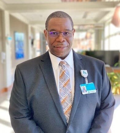 Professional headshot of Melvin Crawford in business suit at healthcare facility