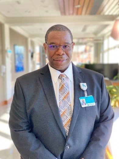 Professional headshot of Melvin Crawford in business suit at healthcare facility