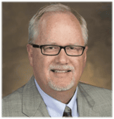 Professional headshot of Michael Brendel wearing glasses and gray suit jacket