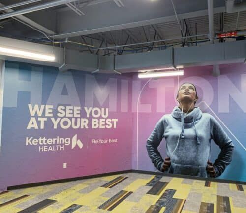 Kettering Health wall mural featuring woman in hoodie with "We See You At Your Best" message