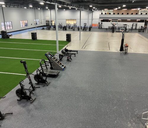 Modern fitness facility with weight equipment, turf area, and basketball court