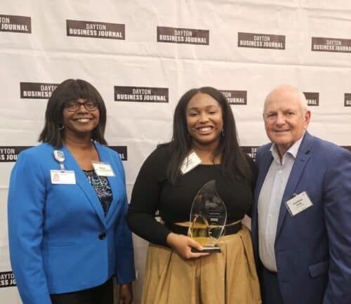 Three people posing with award at Dayton Business Journal event backdrop