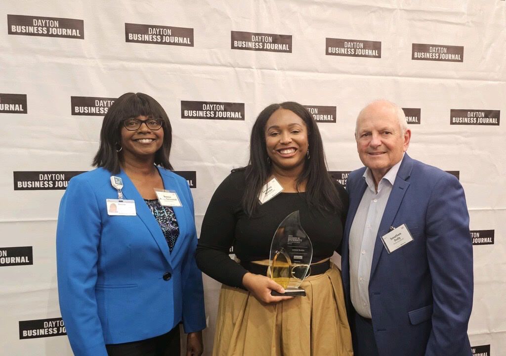 Three people posing with award at Dayton Business Journal event backdrop