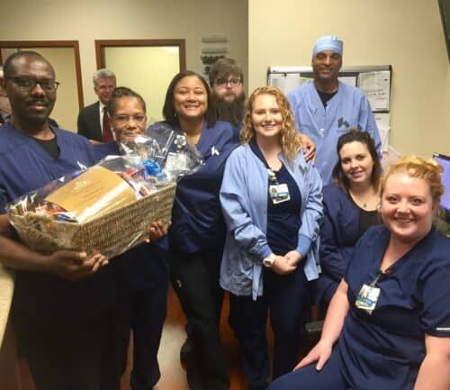 Healthcare team celebrating with gift basket presentation in medical facility