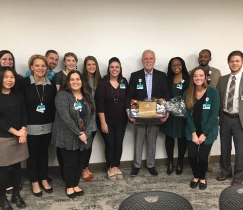 Group of healthcare professionals posing together, with one person holding a gift basket.