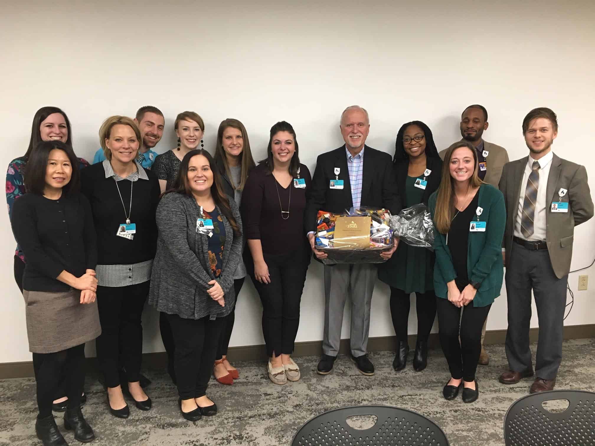 Group of healthcare professionals posing together, with one person holding a gift basket.