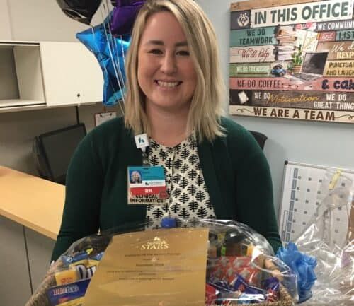 Healthcare employee receiving Employee of the Month award with certificate and gift basket