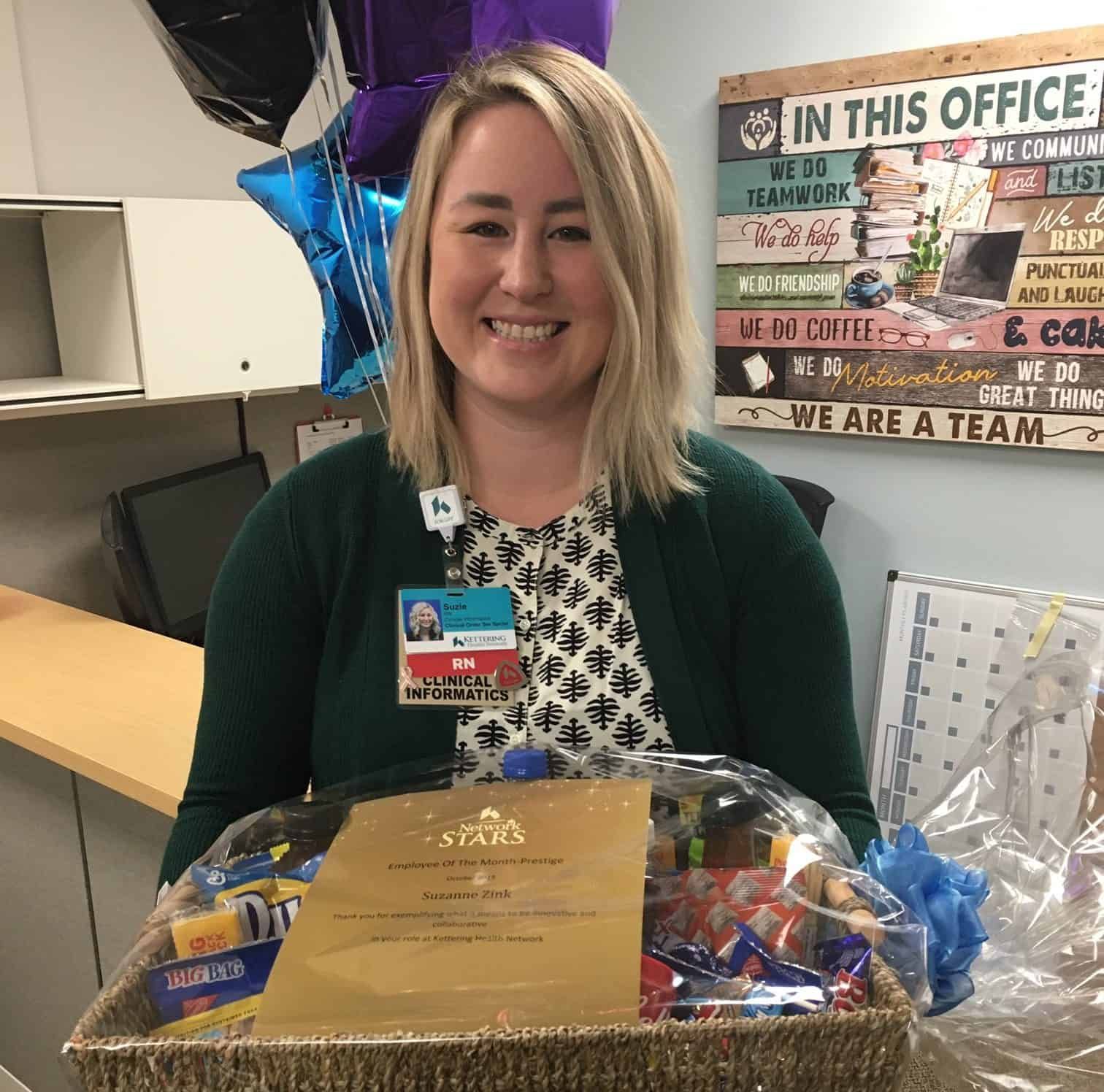 Healthcare employee receiving Employee of the Month award with certificate and gift basket