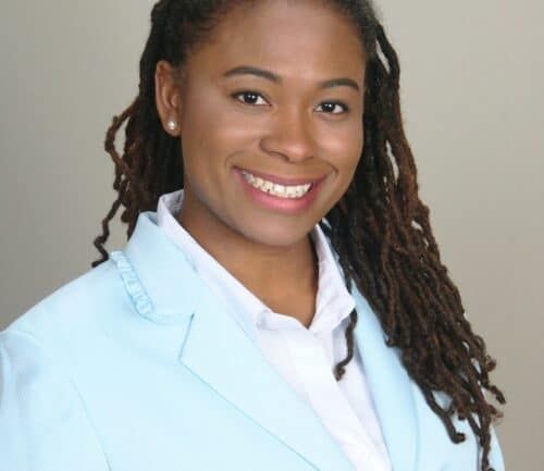 Professional headshot of healthcare provider with dreadlocks wearing light blue blazer and white shirt