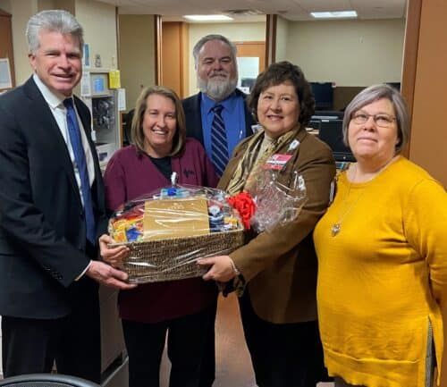 Five healthcare professionals presenting gift basket to employee recognition recipient
