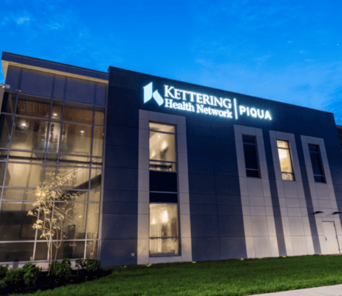 Modern Kettering Health Network Piqua hospital building exterior at dusk with illuminated signage