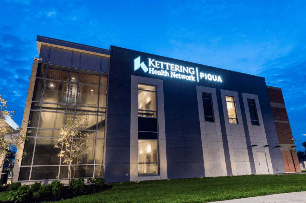 Modern Kettering Health Network Piqua hospital building exterior at dusk with illuminated signage