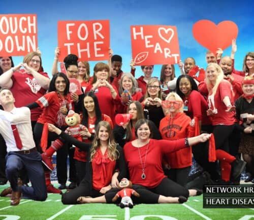Large group of Kettering Health employees in red clothing holding heart disease awareness signs
