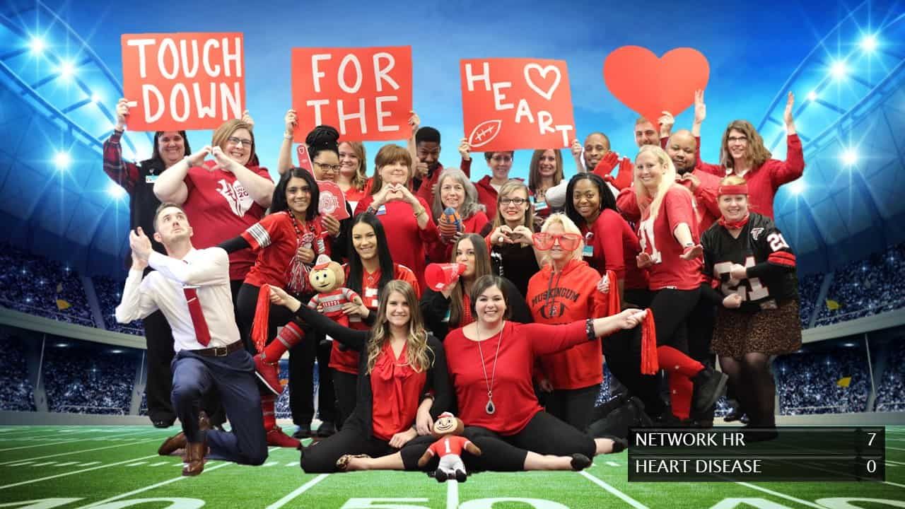 Large group of Kettering Health employees in red clothing holding heart disease awareness signs