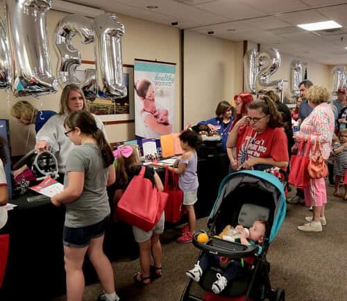 Families with children gather at healthcare safety fair with balloons and informational booths