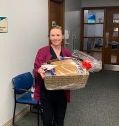 Healthcare worker Sarah Denney holding gift basket in medical office setting