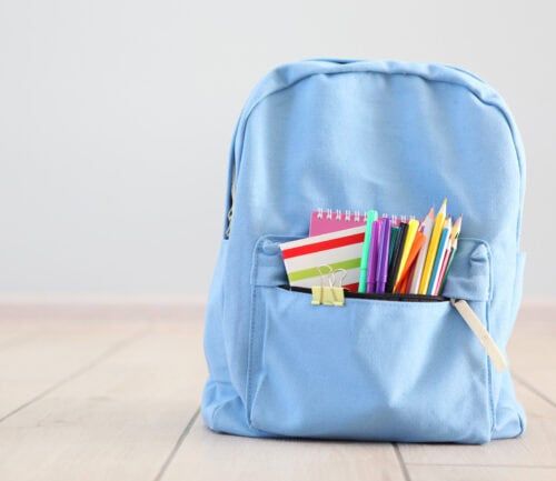 Blue school backpack filled with colorful pencils, notebooks and school supplies