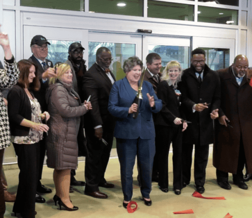 Group of officials cutting red ribbon at healthcare facility opening ceremony
