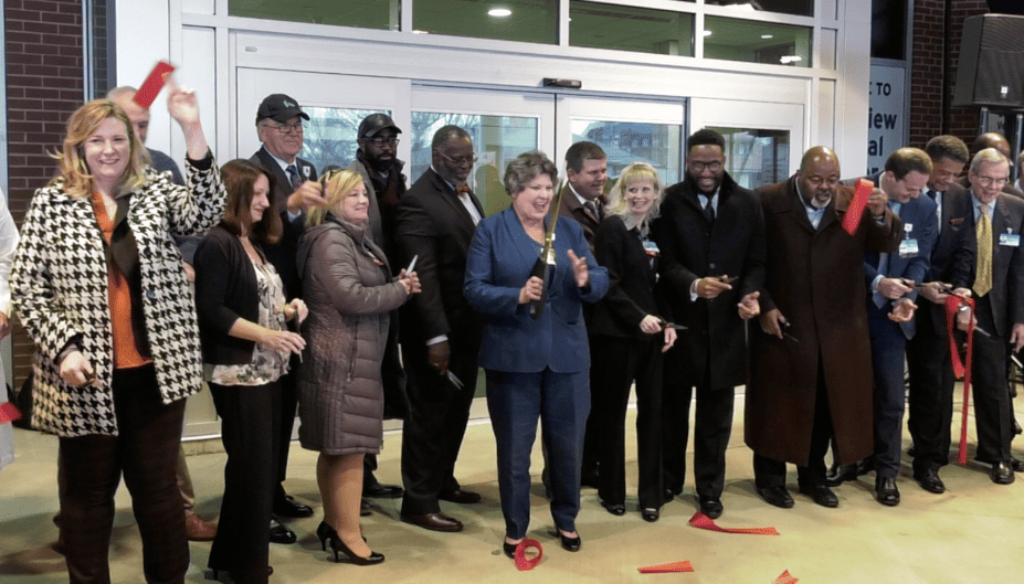 Group of officials cutting red ribbon at healthcare facility opening ceremony