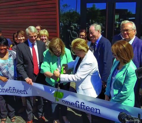 Group of officials cutting ribbon at OneFifteen healthcare facility grand opening ceremony