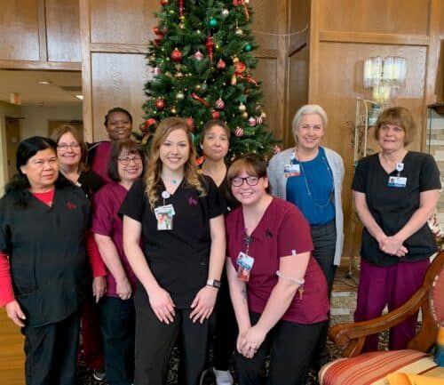 Healthcare team members posing together near Christmas tree in hospital lobby