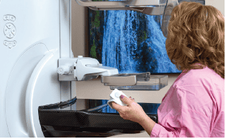 Patient in pink gown receiving MRI scan with relaxing waterfall imagery display