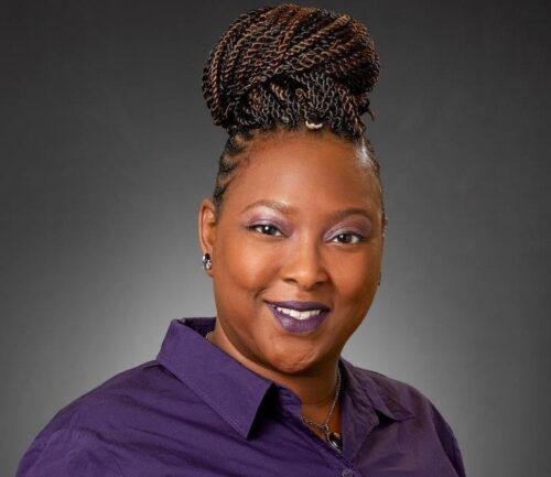 Professional headshot of Shanese Higgins wearing purple shirt against gray background