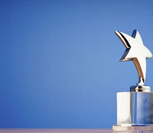 Silver star trophy award on crystal base against blue background