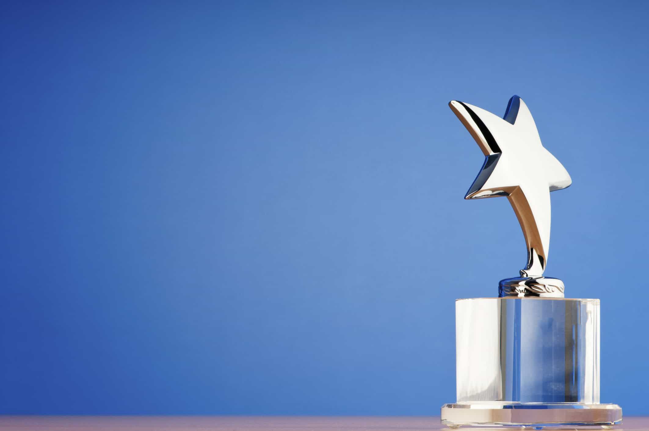 Silver star trophy award on crystal base against blue background