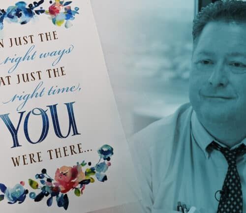 Healthcare worker in business attire next to inspirational card thanking essential workers