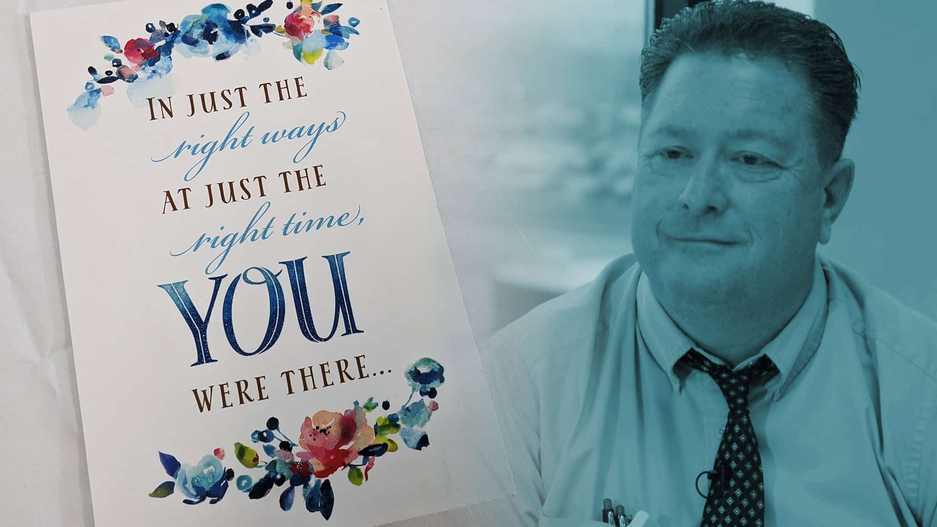 Healthcare worker in business attire next to inspirational card thanking essential workers