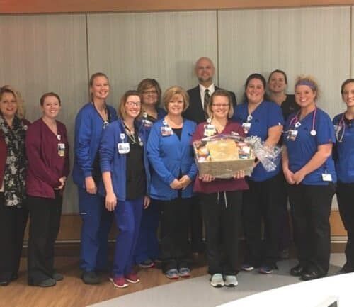 Healthcare team celebrating Employee of the Month award with certificate presentation
