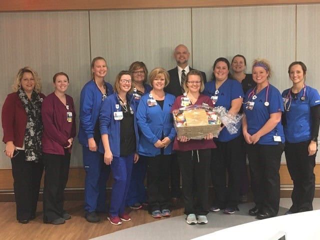 Healthcare team celebrating Employee of the Month award with certificate presentation