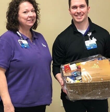 Two healthcare workers pose together, one holding a gift basket
