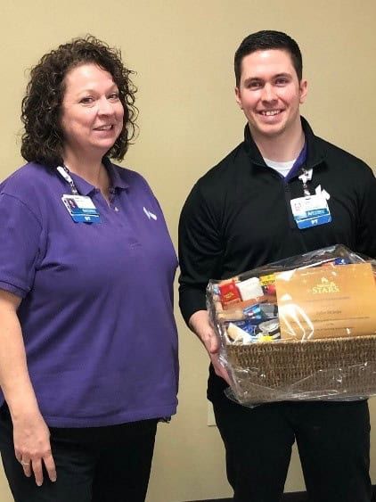 Two healthcare workers pose together, one holding a gift basket
