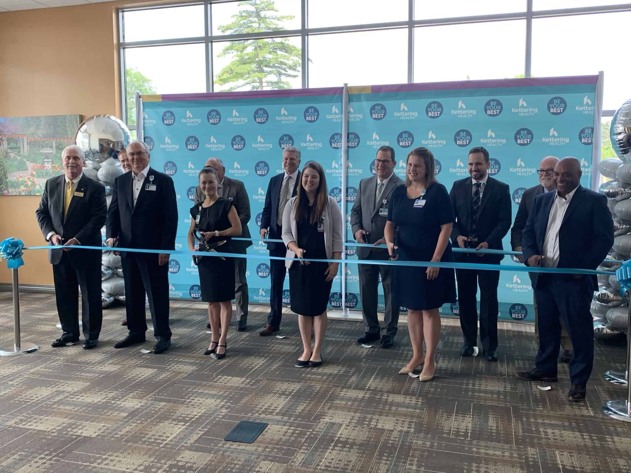 Group of executives participating in ribbon cutting ceremony at Kettering Health facility opening