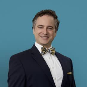 Professional headshot of Aaron Berenson, MD in navy suit with yellow bow tie