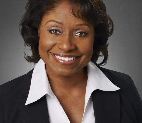 Professional headshot of Anita Adams wearing black blazer and white shirt, smiling warmly.