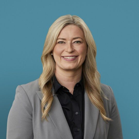 Professional headshot of Amber Orellana, APRN-CNP in gray blazer and black shirt
