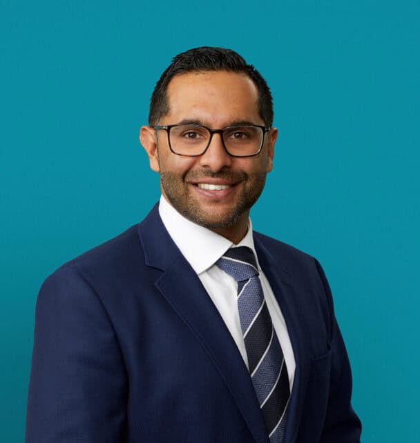 Professional headshot of Dr. Avneil S. Yashpal in navy suit against teal background