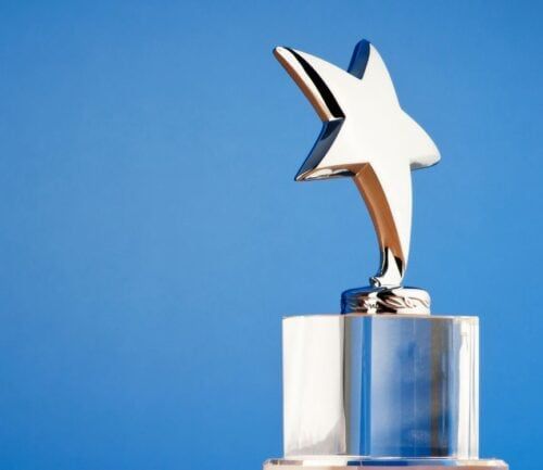 Polished star-shaped trophy award on crystal base against blue background