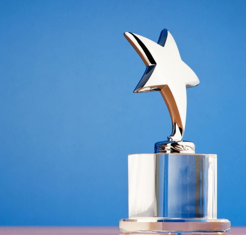 Polished star-shaped trophy award on crystal base against blue background