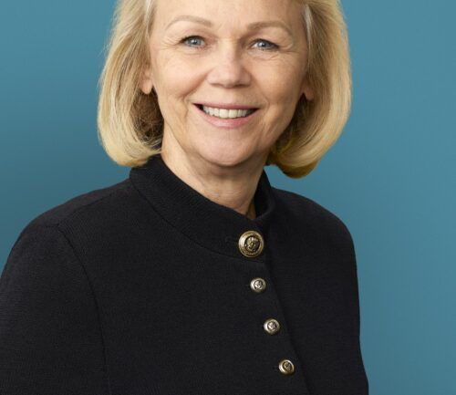 Professional headshot of woman in black cardigan with gold buttons smiling warmly