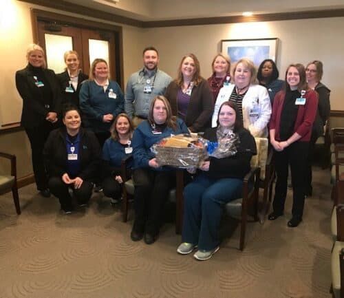 Healthcare team members gathered together holding gift baskets in hospital waiting area