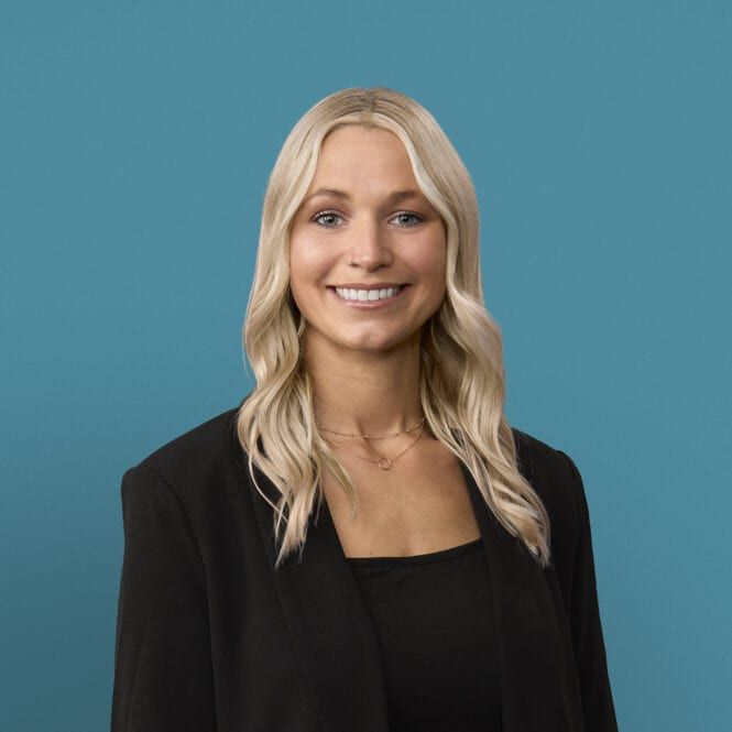 Professional headshot of Courtney Nelson, APRN-CNP, smiling in black blazer against blue background